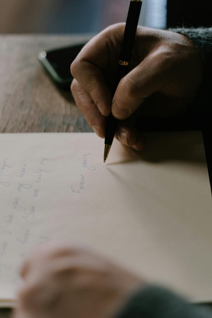 Close-up photo capturing person handwriting on paper with a pen.